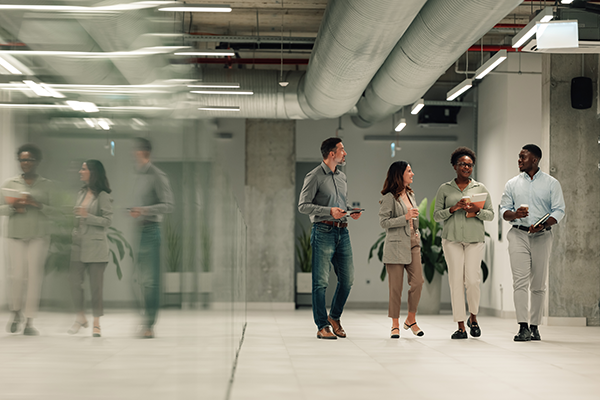 Group of professionals walking and collaborating in a modern office hallway.