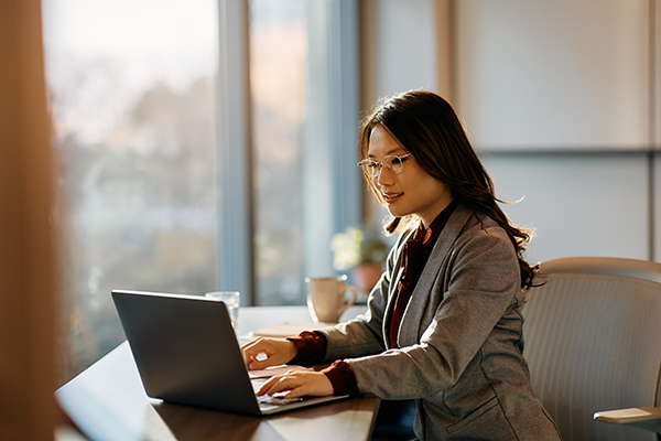 Professional working on a laptop at a desk in a modern office with natural light.