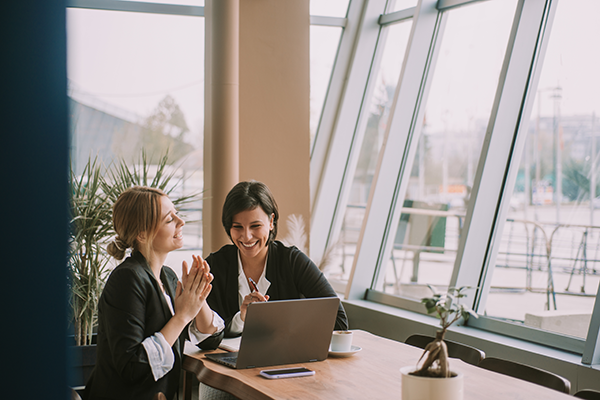 Professionals collaborating at a table with a laptop in a bright office setting.