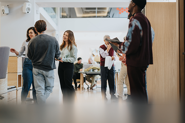 Professionals interacting and collaborating in a busy open office environment.