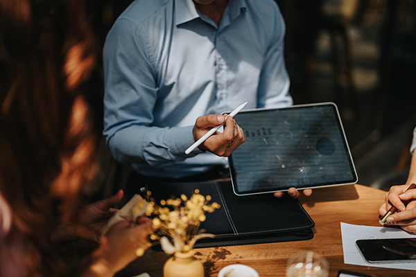 Professional presenting data on a tablet during a workplace discussion.