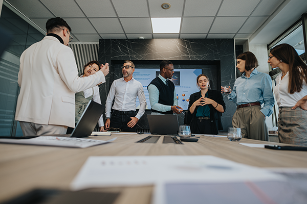 Professionals standing and discussing information during a meeting in a modern conference room.
