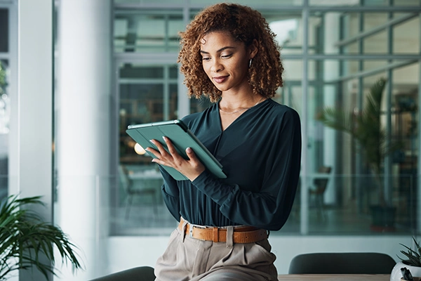 Professional using a tablet while seated in a modern office space.