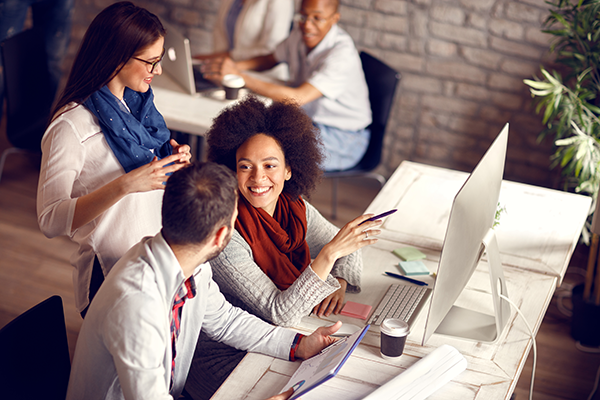 Professionals collaborating around a desk with documents and a computer in a modern office environment.