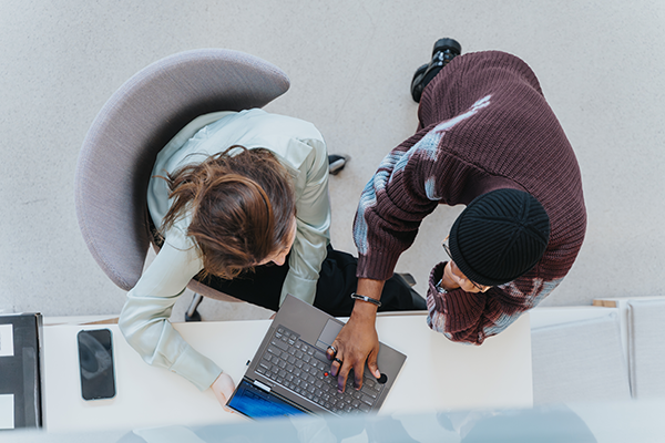 Overhead view of professionals collaborating around a desk while working on a laptop in a modern office.