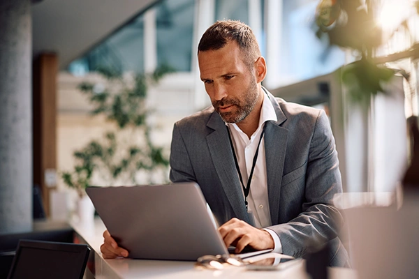 Professional working on a laptop at a desk in a modern office environment.