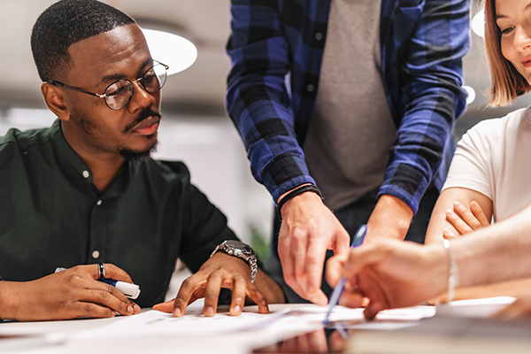 Professionals reviewing documents together while pointing at information during a meeting.
