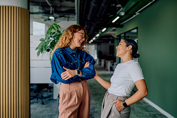 Two professionals standing and interacting in a modern office hallway.