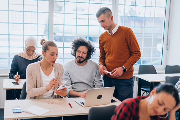Professionals collaborating around a table with a laptop and notes in a modern workspace.