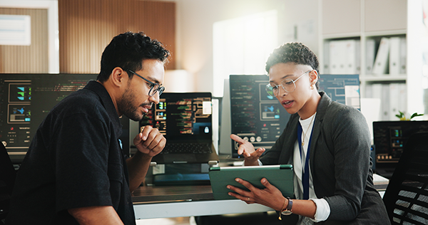 Professionals reviewing data on a tablet in a technology-focused office environment.