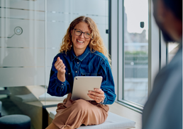 Professional holding a tablet during a meeting in a modern office.