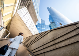 Person walking through a modern business district surrounded by high-rise office buildings.