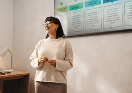 Person presenting information beside a screen in a meeting room.