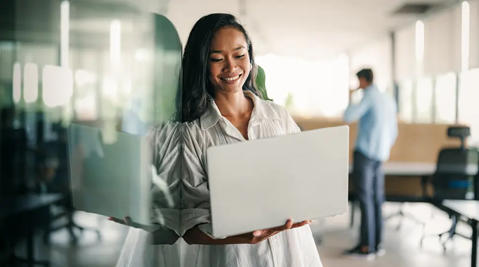 Person standing in a modern office using a laptop.