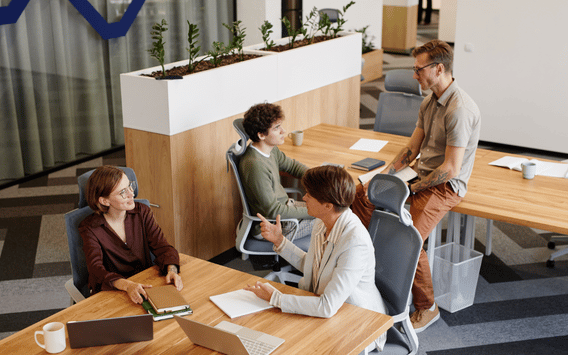 Colleagues collaborating around desks in a modern open-plan office.
