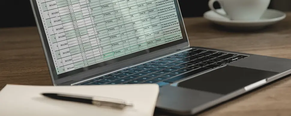 Laptop displaying spreadsheet data on a desk.