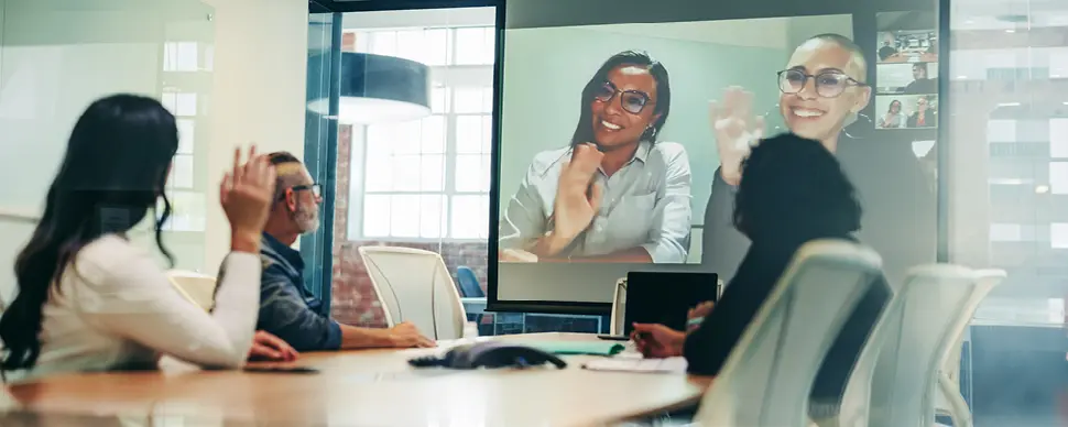 Hybrid meeting with in-person and remote participants on a video call.
