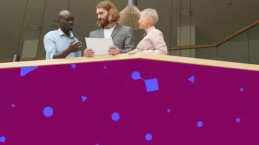 Professionals reviewing documents together from a balcony in a modern office.