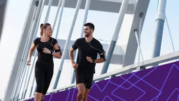wo people jogging side by side on a modern bridge.