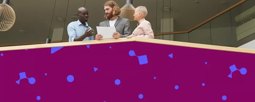 Professionals reviewing documents together from a balcony in a modern office.