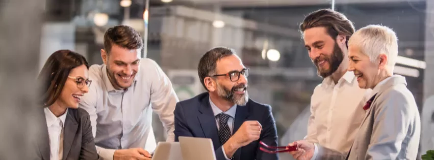 a group of people laughing and talking in the office