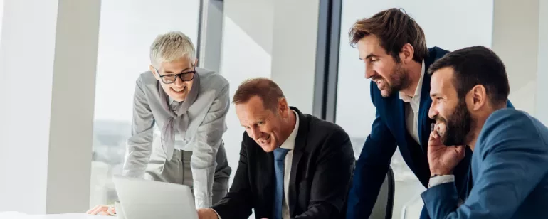 a group of people smiling looking to a computer in an office