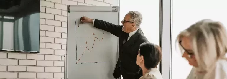 Professional presenting data trends on a flip chart during a workplace meeting