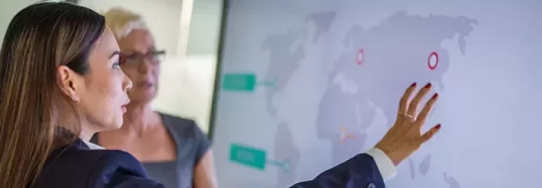 Professionals reviewing global data on a digital screen during a workplace discussion.