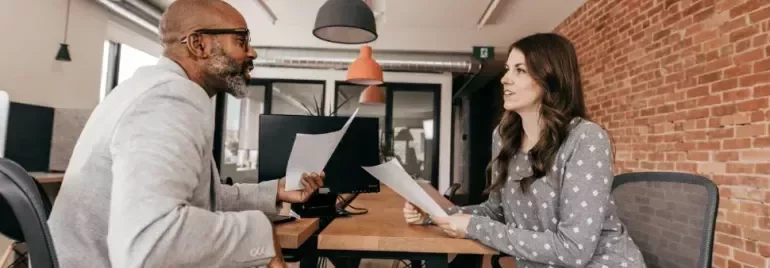 Two professionals reviewing documents together during a meeting in a modern office