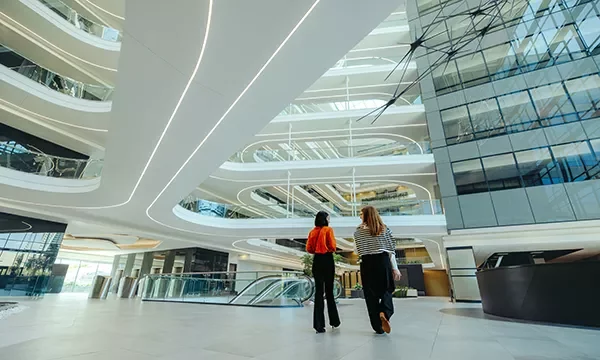 Two professionals walking through a large modern building atrium with open architectural design.