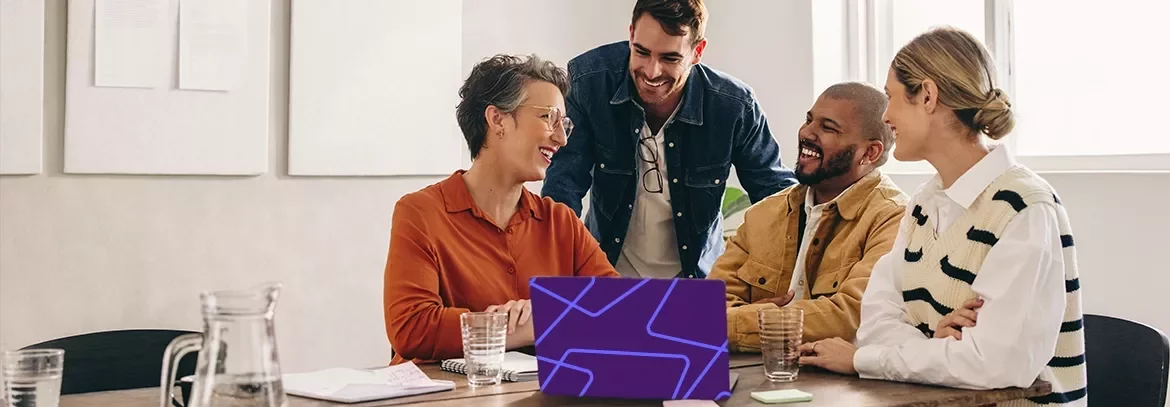 Professionals collaborating around a laptop during a meeting in a modern office.