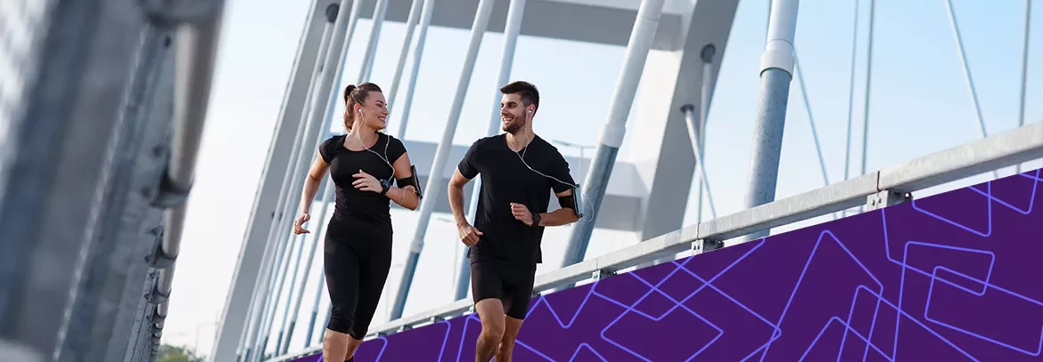 wo people jogging side by side on a modern bridge.